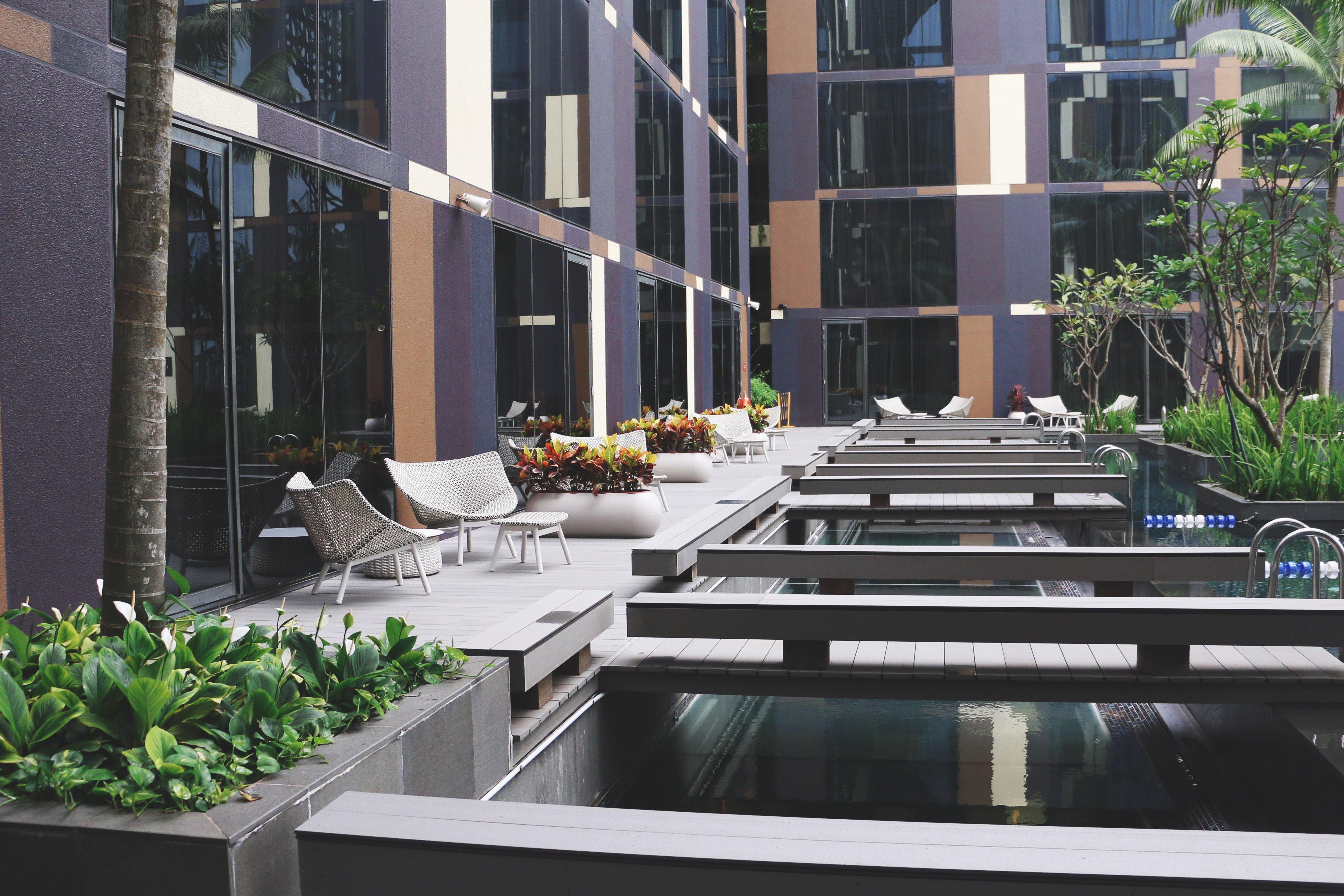Crowne Plaza Changi Airport By Ihg Сінгапур Екстер'єр фото The photo shows a modern outdoor area featuring a sleek, contemporary design. There are large glass windows reflecting the surroundings, and the space includes wooden decks over water features. Comfortable seating areas are arranged along the decking