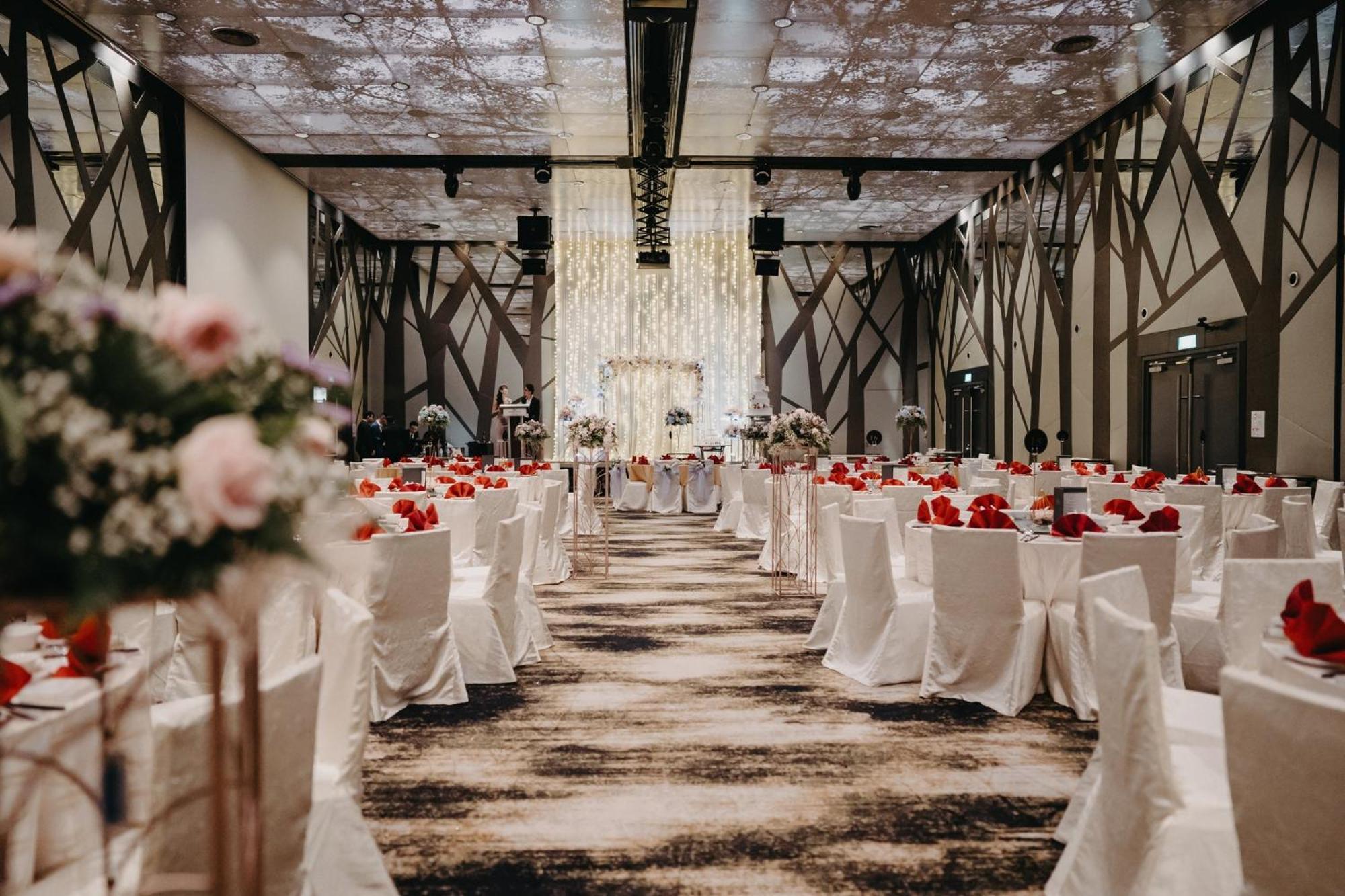Crowne Plaza Changi Airport By Ihg Сінгапур Екстер'єр фото The photo shows an elegantly decorated banquet hall set up for an event, likely a wedding or formal gathering. The room features rows of tables covered in white tablecloths, each adorned with vibrant red flowers. There are also floral arrangements on