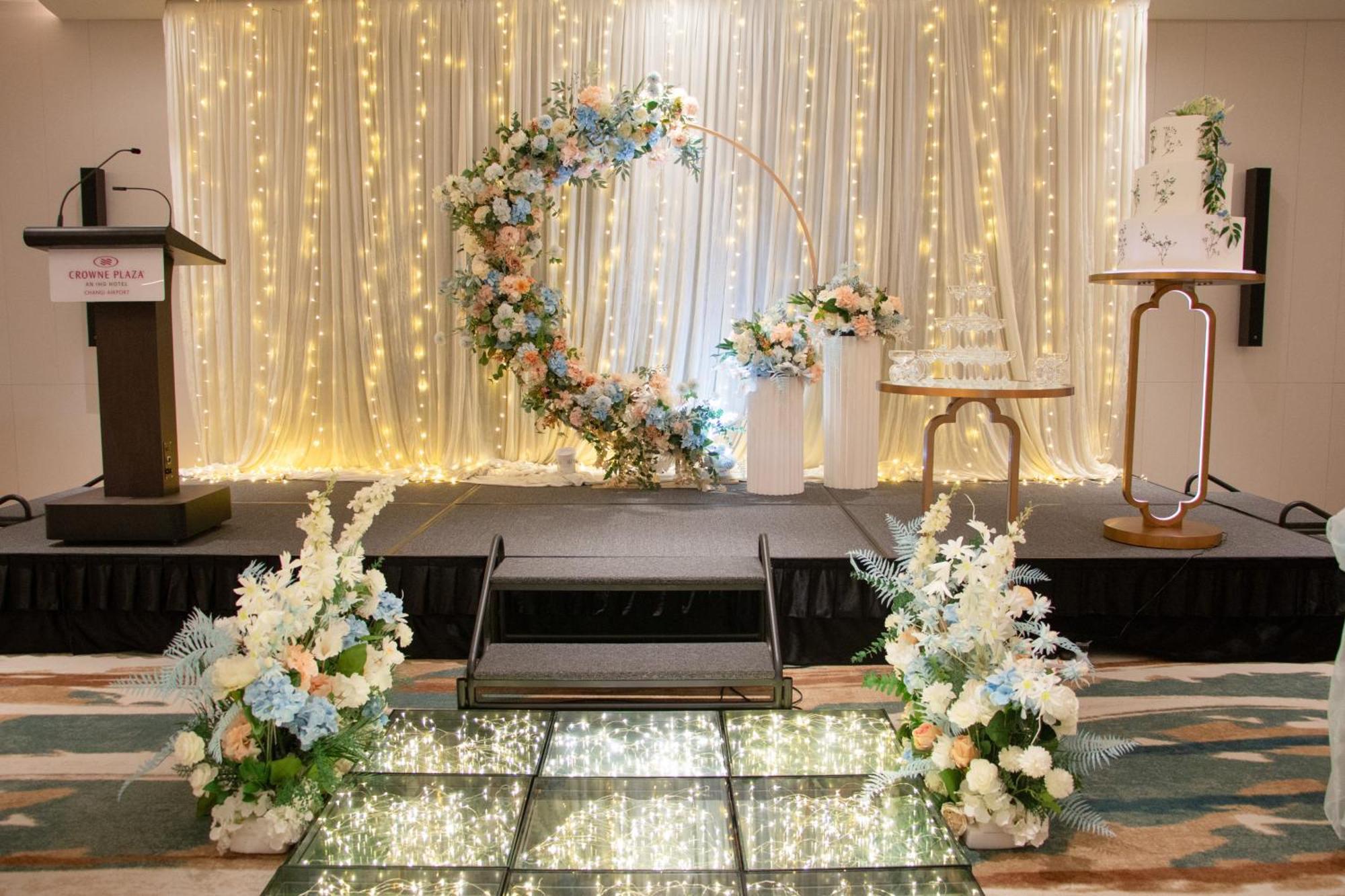 Crowne Plaza Changi Airport By Ihg Сінгапур Екстер'єр фото The photo shows a beautifully decorated event space, likely for a wedding or special occasion. In the background, there is a shimmering curtain with fairy lights that create a warm, romantic ambiance. 

At the center, there is a circular floral arch 