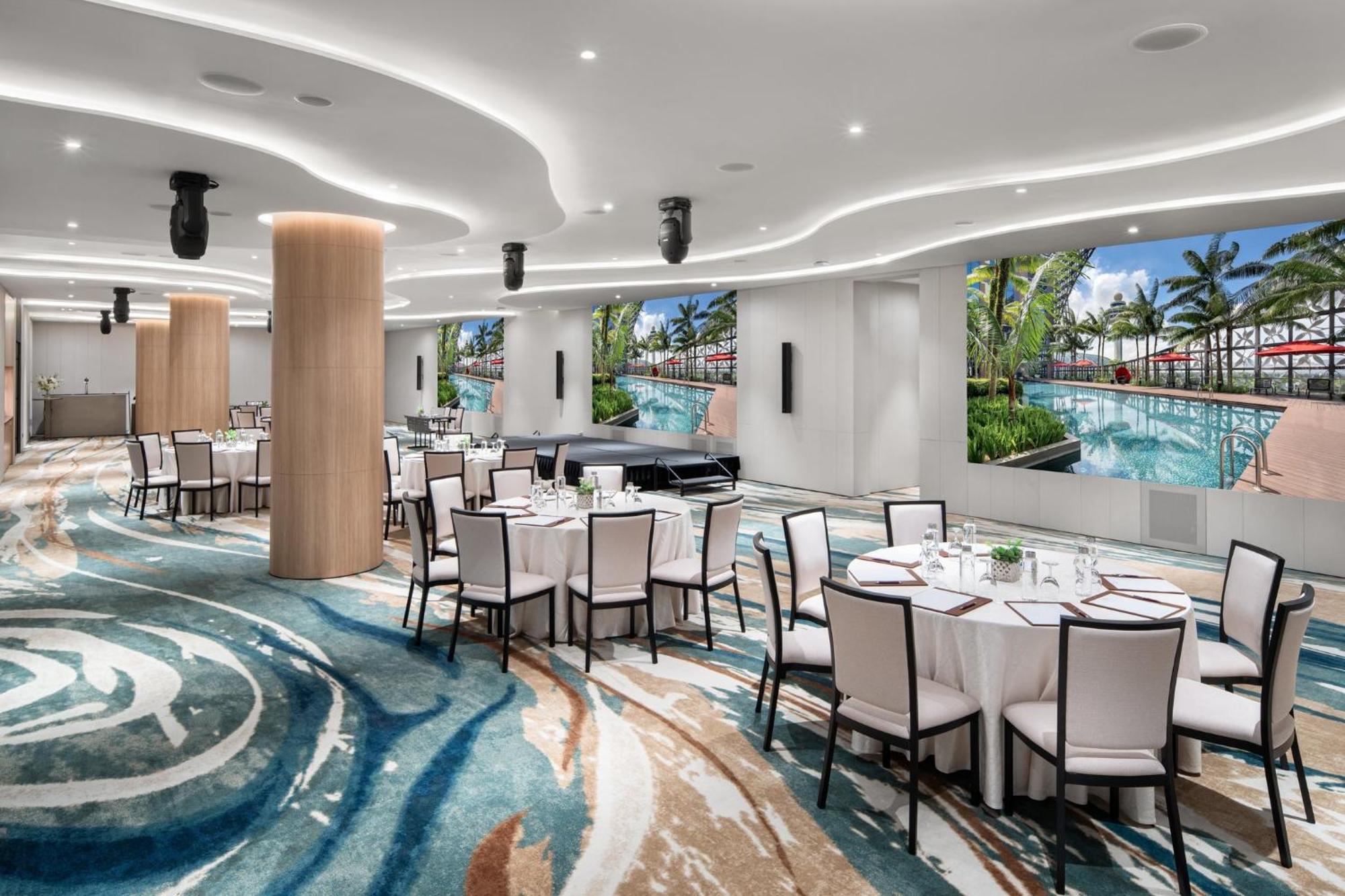 Crowne Plaza Changi Airport By Ihg Сінгапур Екстер'єр фото The photo showcases a modern event space or dining area. It features several round tables covered with white tablecloths and set with dishes and utensils. The floor has an eye-catching design with swirling patterns in various shades of blue and beige